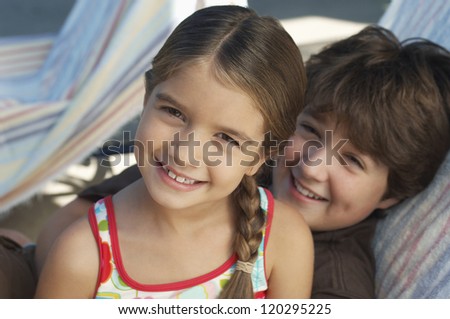 Portrait of a happy brother and sister smiling together while relaxing on deckchair
