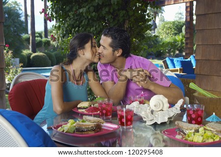 Happy couple about to kiss at dining table in resort