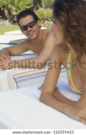 Happy couple relaxing on lounge chairs while looking at each other