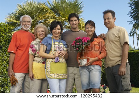 Low angle view of happy family standing together with flower plant at garden