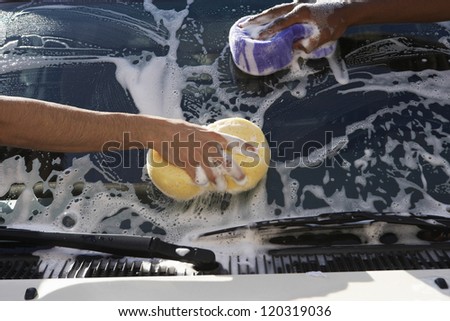 Hands of people washing car with sponge