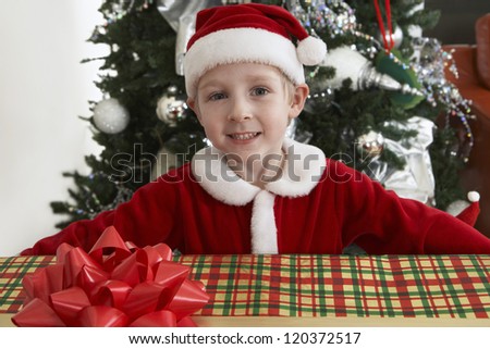 Portrait of happy preadolescent boy in Santa Claus outfit with gift box