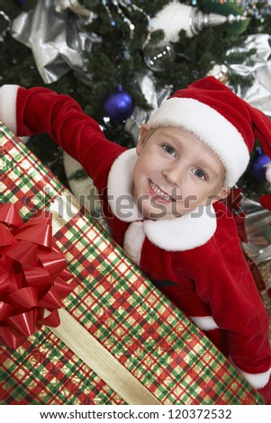 High angle view of happy preadolescent boy in Santa Claus outfit with gift box