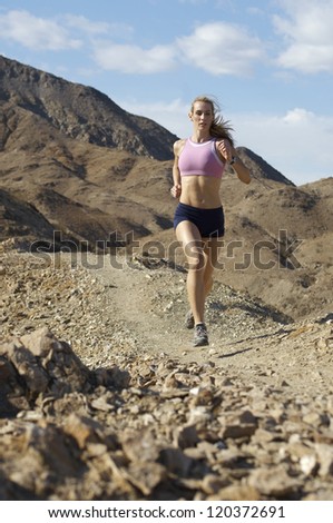 Full length of a beautiful Caucasian woman jogging in mountains