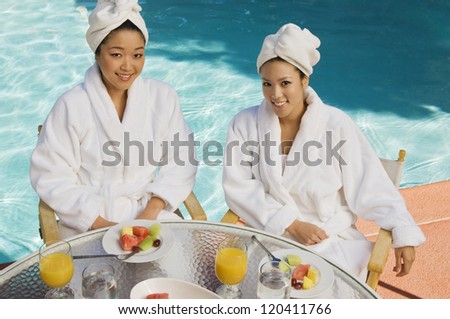 High angle view of two female friends having breakfast together by the pool side