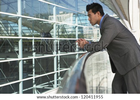 Side view of a thoughtful businessman leaning on railing outside office