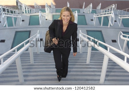 Full length portrait of a beautiful business woman climbing stairs