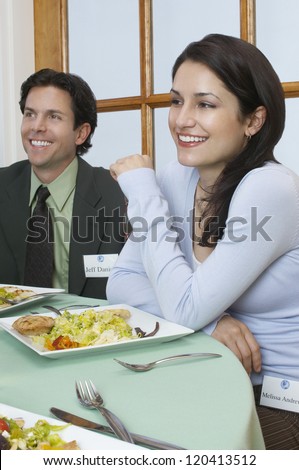 Two happy successful businesspeople sitting together at dining table