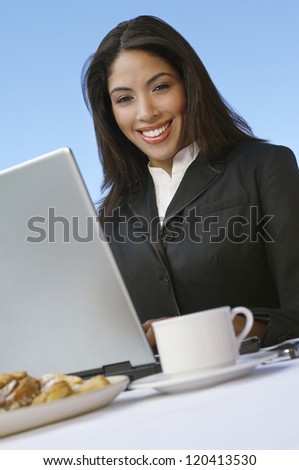 An African American businesswoman sitting with laptop and cup of tea