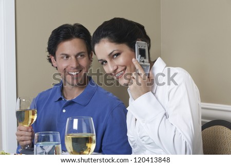 Portrait of a beautiful Caucasian woman on call and man with wine in the background
