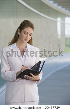 Beautiful businesswoman writing notes in dairy