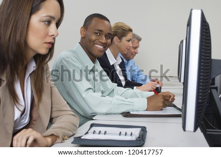 Portrait of an African American man writing notes with colleagues working together in office