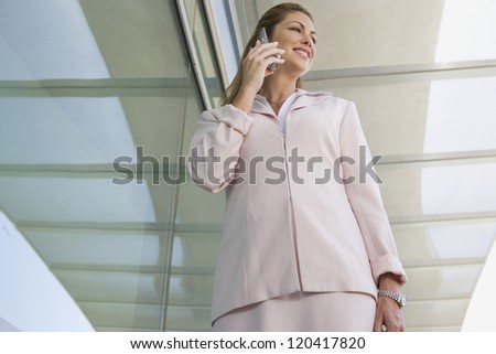Low angle view of a Caucasian successful businesswoman using mobile phone with ceiling in the background
