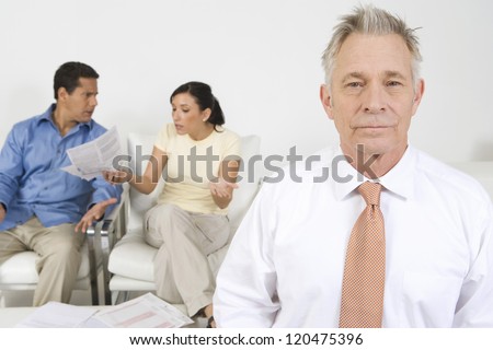 Senior financial adviser with couple discussing in background