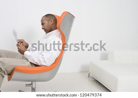 Male executive on modern chair reading document