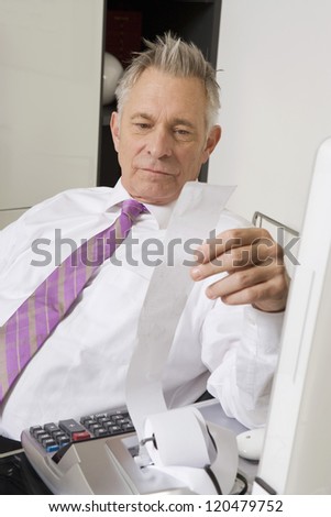 Caucasian businessman reading expense bill in the office