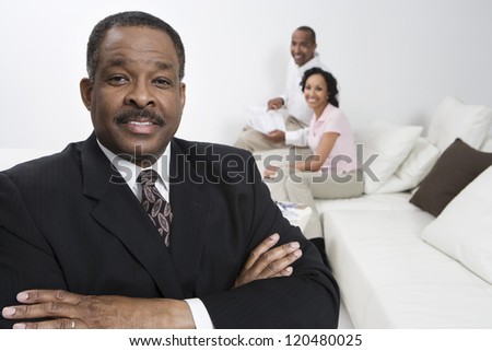 Portrait of confident financial adviser with happy couple in background