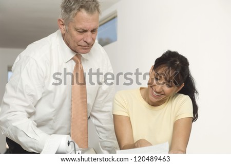 Senior adviser in discussion with happy middle aged woman over financial documents