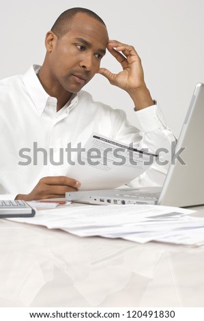 Stressed businessman paying bills through internet at office