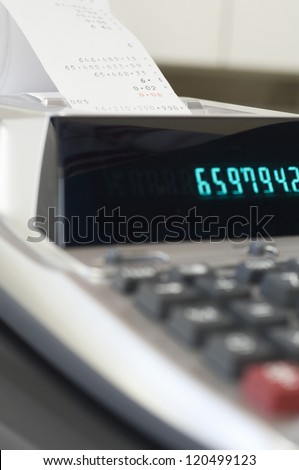 Close up of desktop calculator printing out expenditure receipt