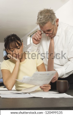 Female client holding document while senior financial adviser reading document in office