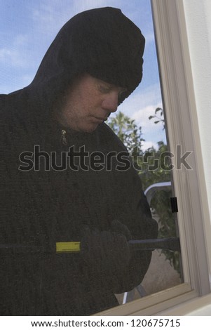 Thief trying to open the window with crowbar