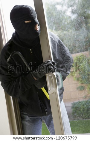 Thief with crowbar opening the door of house