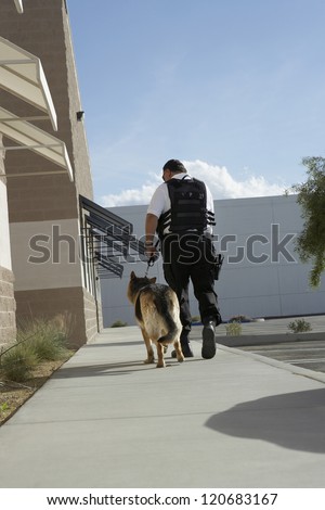 Rear view of a police man walking with dog