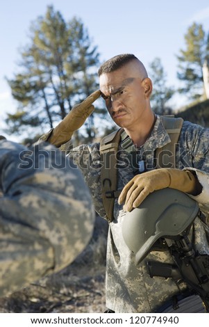 Male soldier saluting to troops outdoors