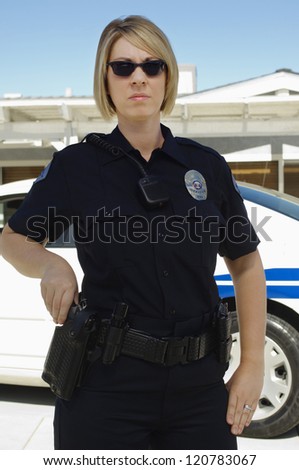 A female police officer standing by car outdoors