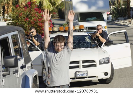 Young man surrendering in front of two police officers