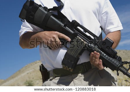 Midsection of a man holding gun