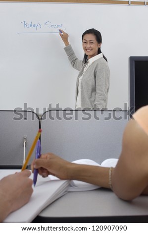 Mature professor writing on white board in classroom
