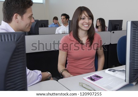 Happy students looking at monitor in classroom