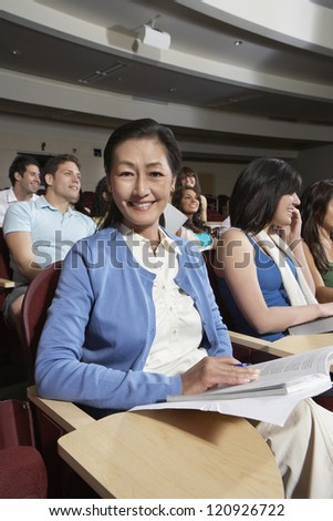 Happy Asian woman sitting with classmates in classroom