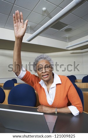Senior woman raising hand while sitting in classroom