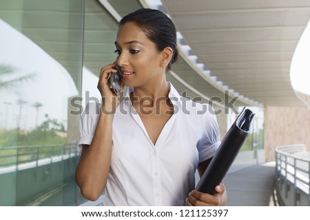 An Indian business woman holding folder while communicating on mobile phone