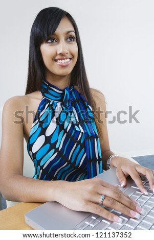 Happy Indian business woman working on laptop at office