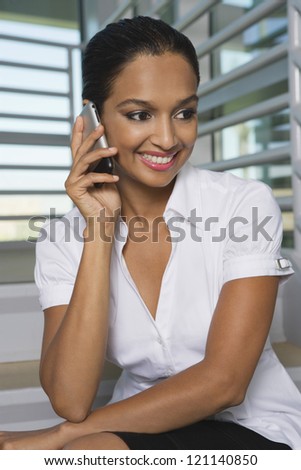 Portrait of a happy Indian business woman communicating on mobile phone at office