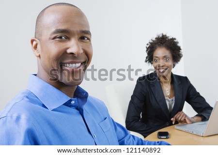 Portrait of a happy African American businessman with female coworker in the background