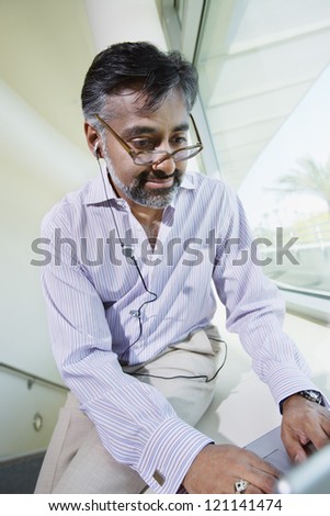 Middle aged Indian businessman using laptop at office