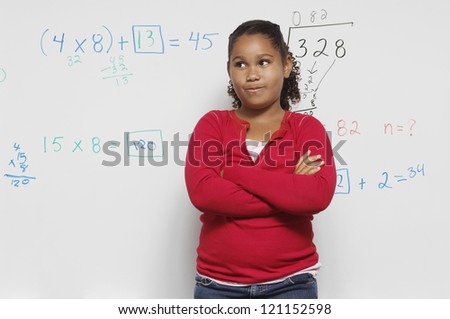 Preadolescent girl standing with hands folded in front of white board