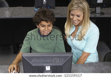 High angle view of happy teenage student using computer while teacher looking