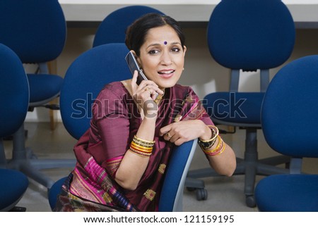 An Indian business woman communicating on cell phone in training room