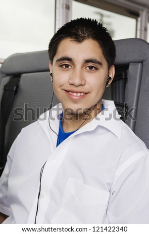Portrait of young male student listening music on MP3 in school bus