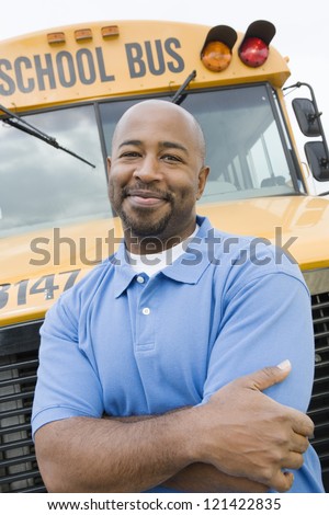 Portrait of a confident driver with arms crossed standing against bus