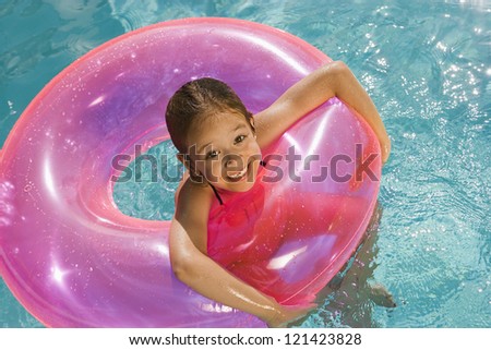 Portrait of a happy Caucasian girl with inflatable tube in swimming pool