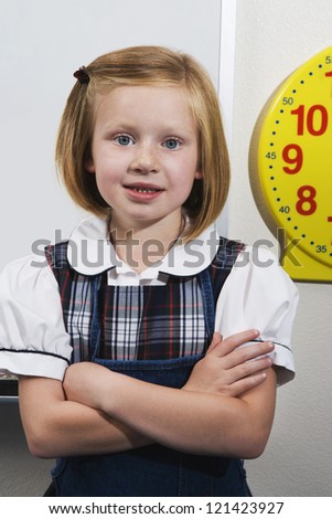 Portrait of a cute little girl in uniform standing with hands folded