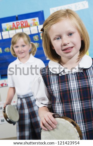 Portrait of little girls with tambourine in music class