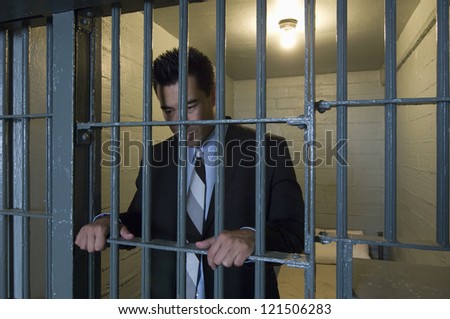 A business man standing behind bars